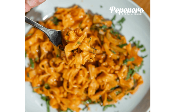 pepeneropizza-furculita-cu-paste-in-prim-plan-cu-o-farfurie-plina-in-fundal